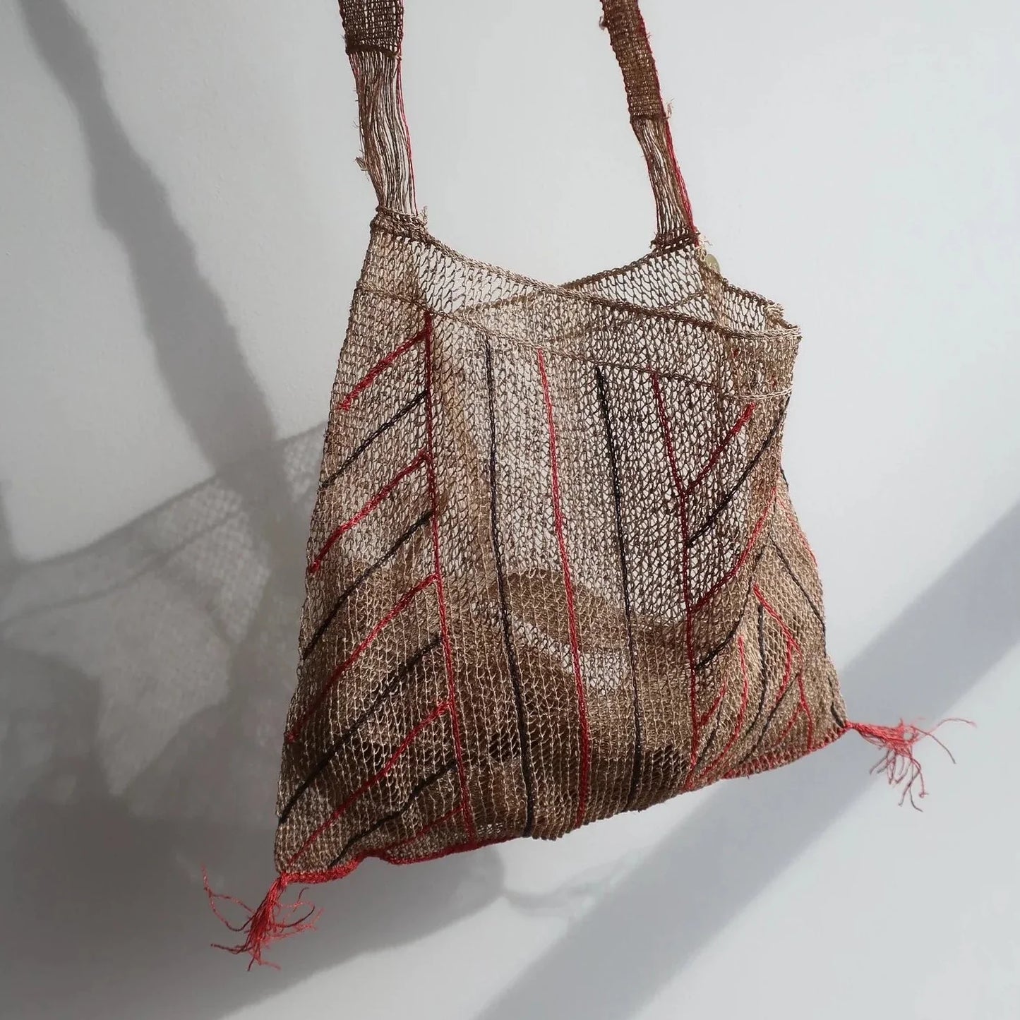 Bolso Kudzu en color natural con rayas en rojo y negro. Asa larga de una sola fibra. se puede llevar de bandolera. Cada Bolso esta hecho a mano y no hay dos bolsos exactamente iguales. Lleva una bolsa interior de lino.  100% natural kudzu vid  Medida: Ancho 38 cm. Alto 30 cm. Asa 115 cm  Hecho a mano en Laos